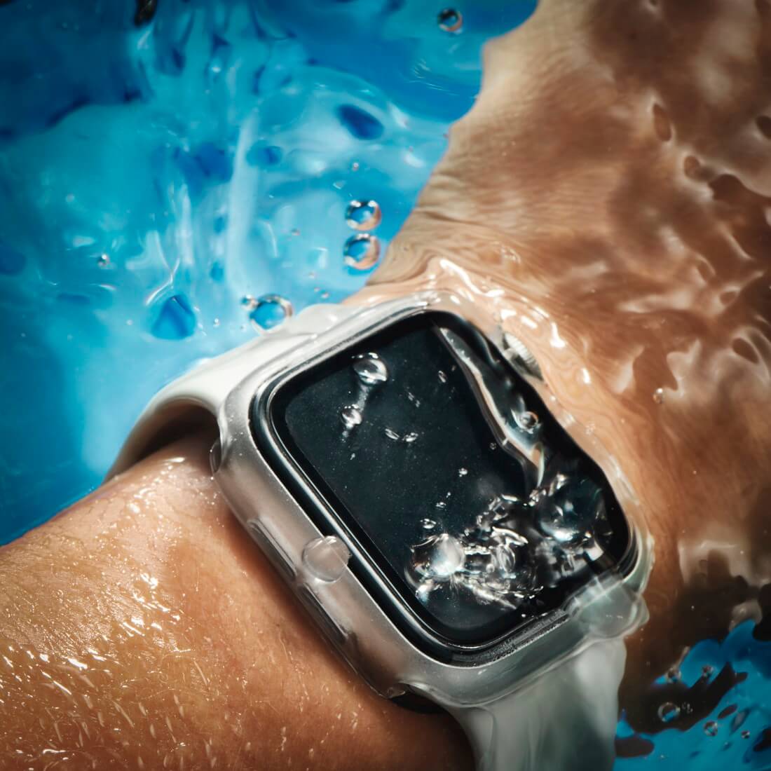 Die Apple Watch 10 42 mm, die am Handgelenk getragen und in blaues Wasser mit Blasen auf dem Bildschirm getaucht wird, bleibt durch die HAMA Schutzhülle für 360°-Rundumsicherheit geschützt.