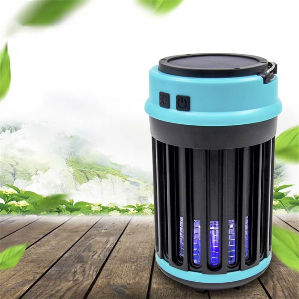 Cover-Discount Moskito-Killer Lampe USB oder Solar mit LED-Licht in Schwarz-Blau steht auf Holz, umgeben von Blättern und einer grünen Landschaft.