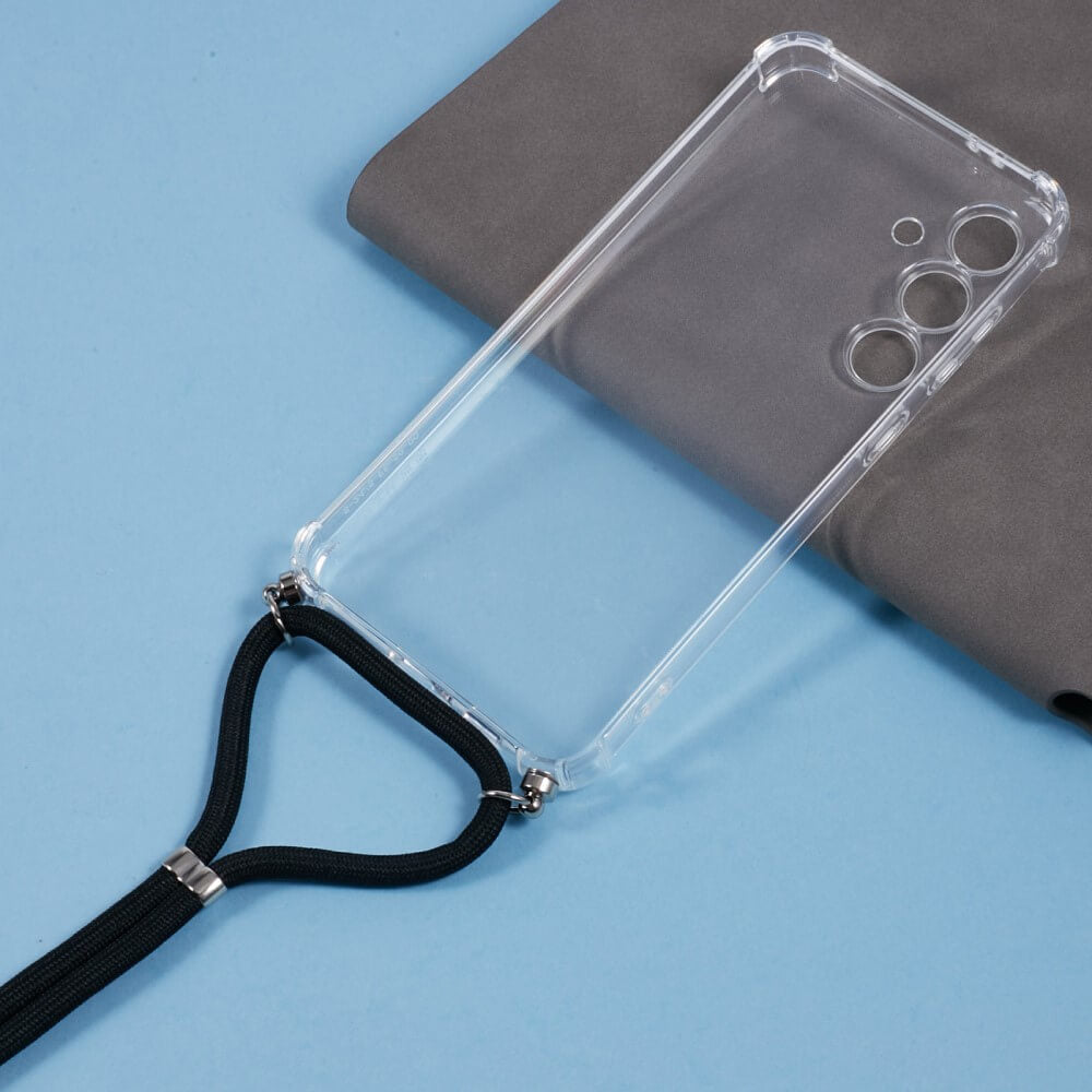 Die Cover-Discount Galaxy S24 FE - Hülle mit Umhängeband in transparentem TPU mit schwarzem Umhängeband liegt auf einer grauen Fläche vor hellblauem Hintergrund.