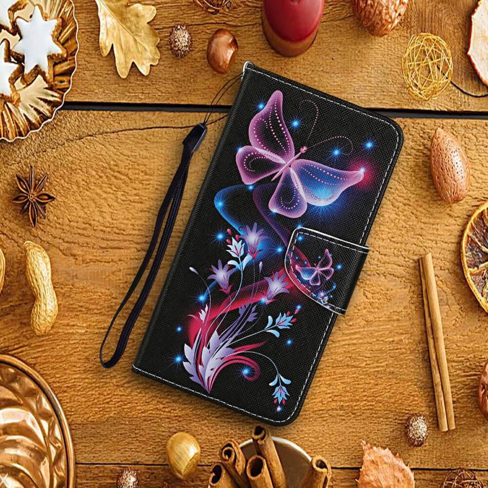 A Galaxy A16 - Tasche Hülle mit Motiv von Cover-Discount in Schwarz mit leuchtendem Schmetterlings-Blumen-Design und praktischen Kartenfächern, präsentiert auf einem Holztisch mit Herbstdeko.