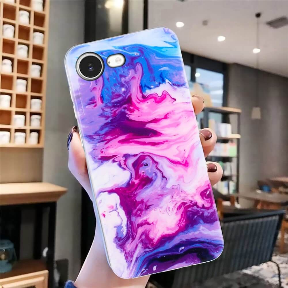 Eine Hand hält ein Telefon mit der Cover-Discount iPhone 16e Silikon Hülle mit Marble Motiv - diese stylische Hülle in Lila, Pink und Blau bietet top Schutz als trendige Handyhülle.