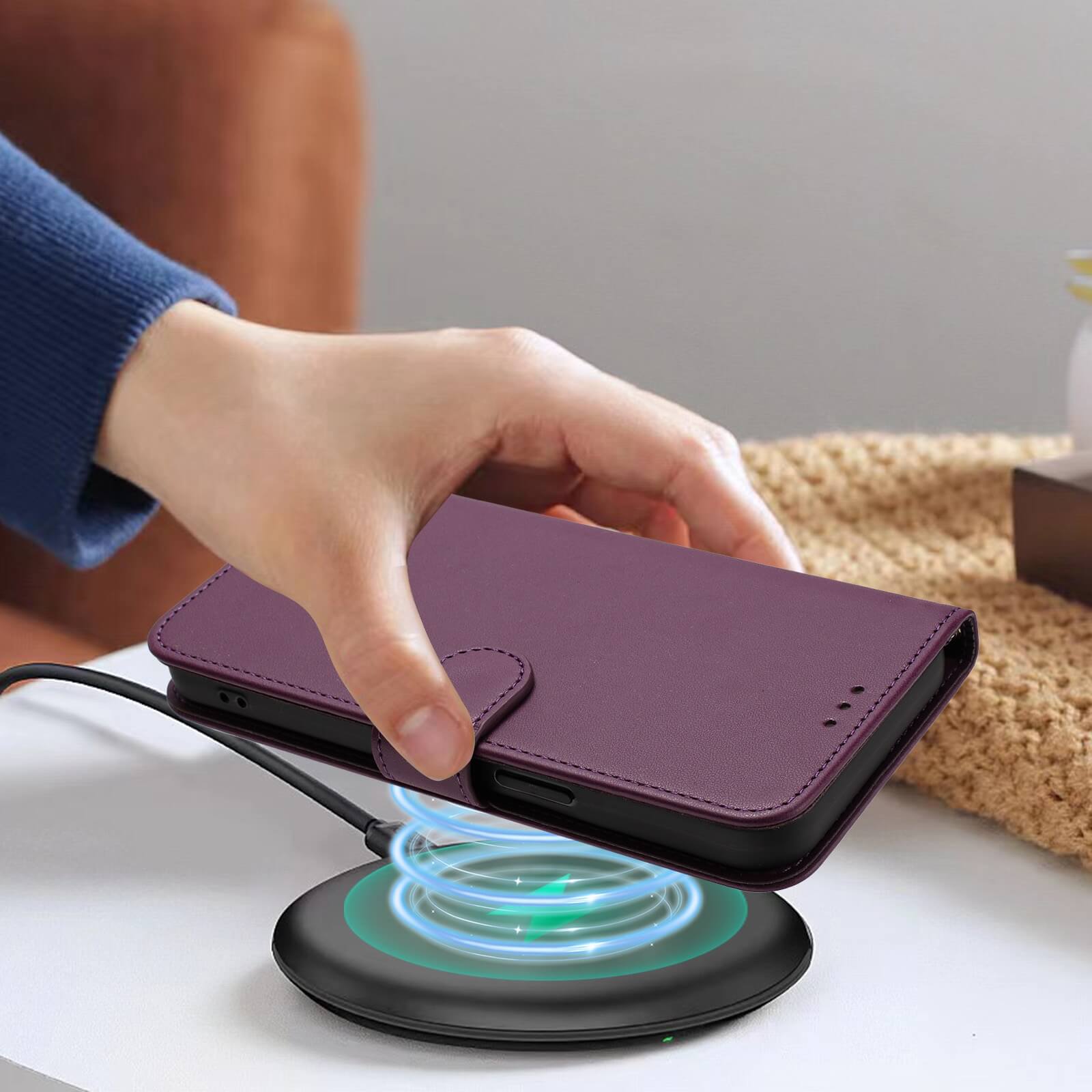 Eine Hand legt das Cover-Discount iPhone 17 Pro - Glänzendes Hüllen Etui mit Handschlaufe in Lila auf ein drahtloses Ladepad auf dem Tisch.