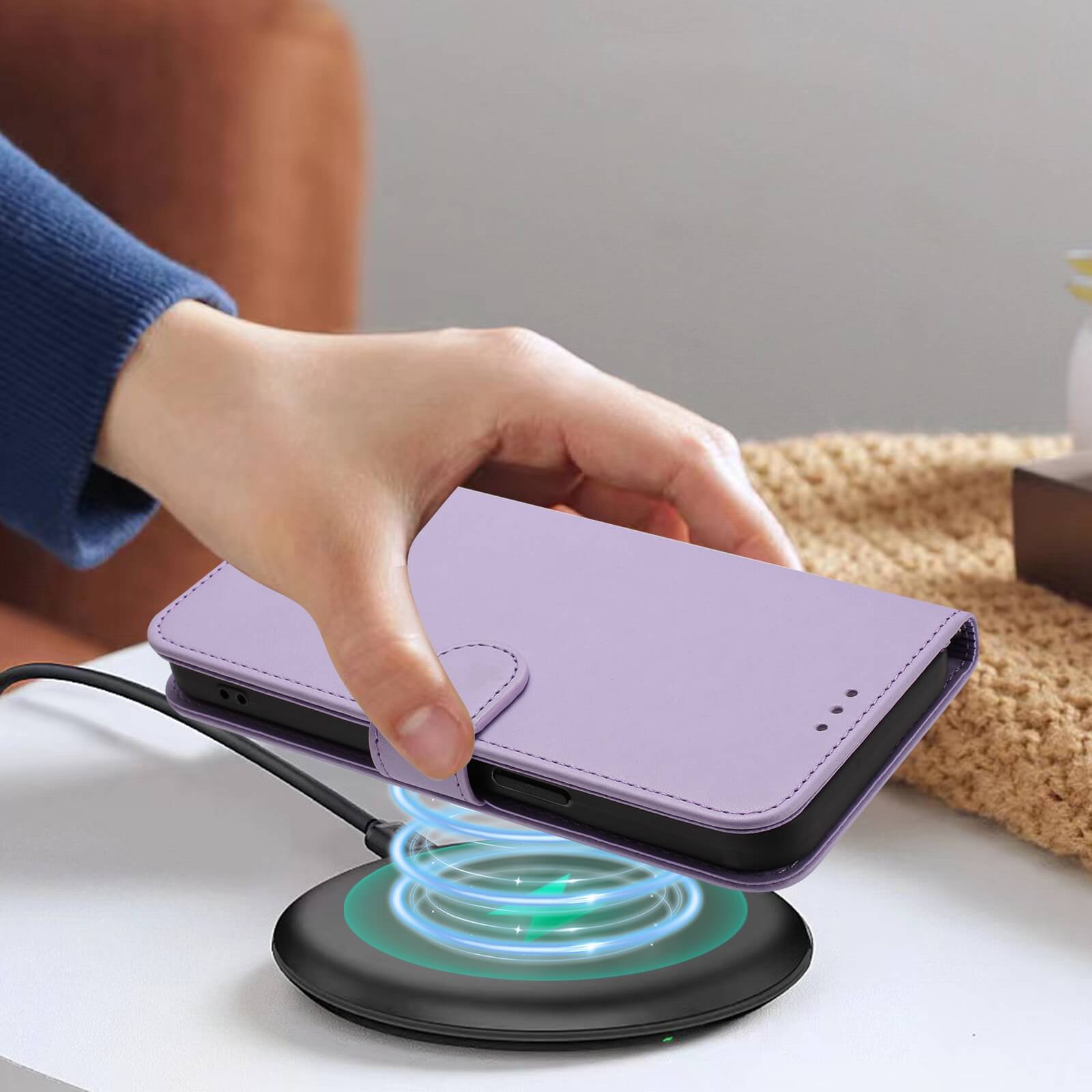 Eine Hand legt ein iPhone 17 Pro in einer Cover-Discount Glänzendes Hüllen Etui mit Handschlaufe Hülle auf ein kabelloses Ladepad.