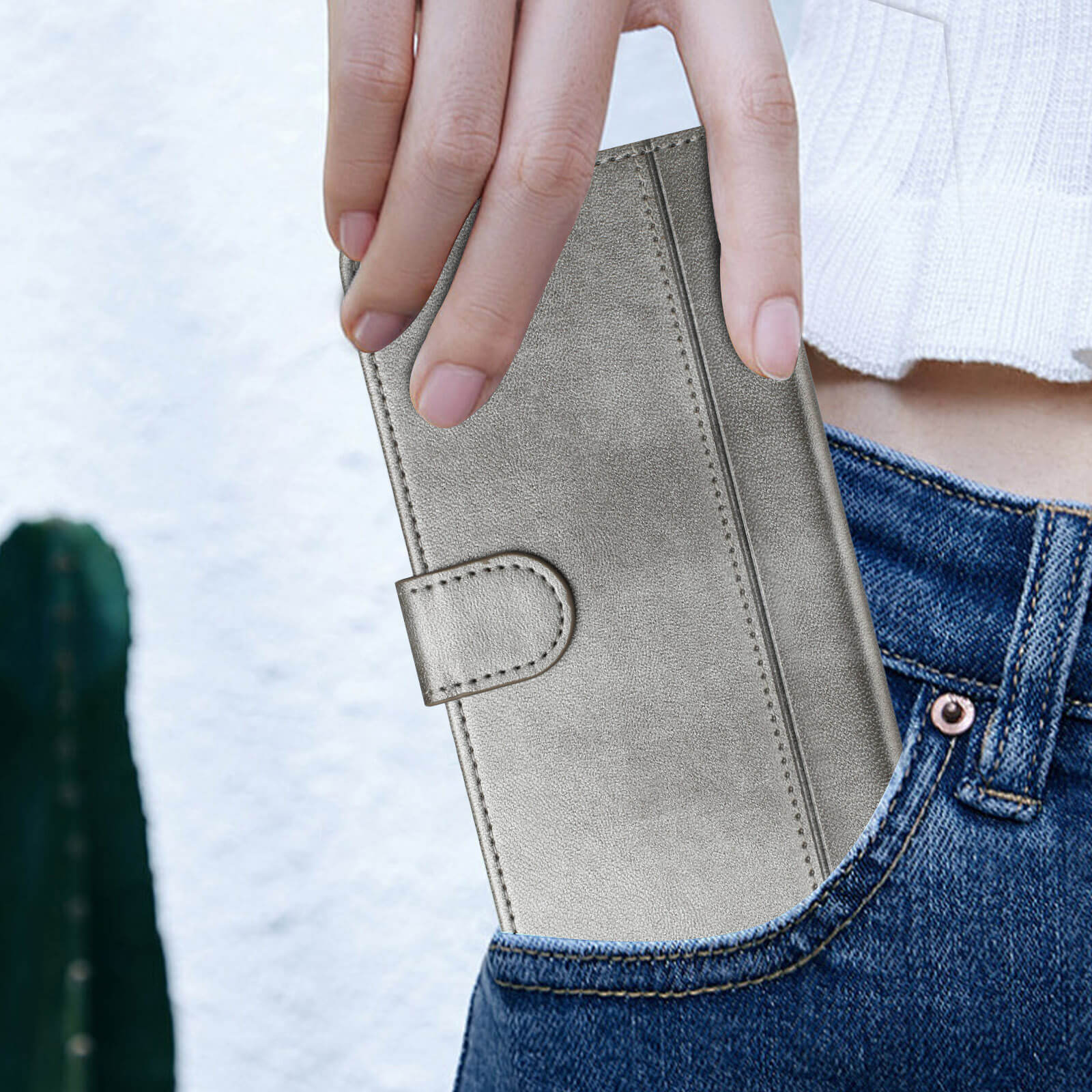 Eine Hand steckt das Cover-Discount iPhone 17 - Retro Look Etui im Vintage Design, das einem klassischen Portemonnaie ähnelt, in die Vordertasche einer Blue Jeans.