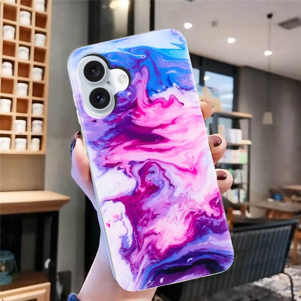 In einem modernen Café hält eine Hand das Cover-Discount iPhone 17 - Silikon Hülle mit Marble Motiv in Lila, Pink und Blau.