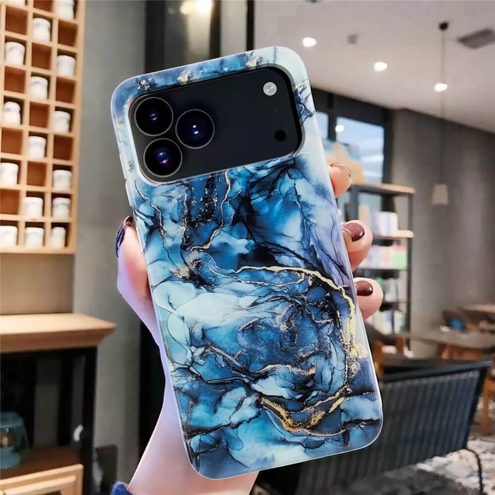 Eine Hand hält eine Cover-Discount iPhone 17 Pro - Silikon Hülle mit Marmor Motiv in Blau in einem modernen Innenraum.