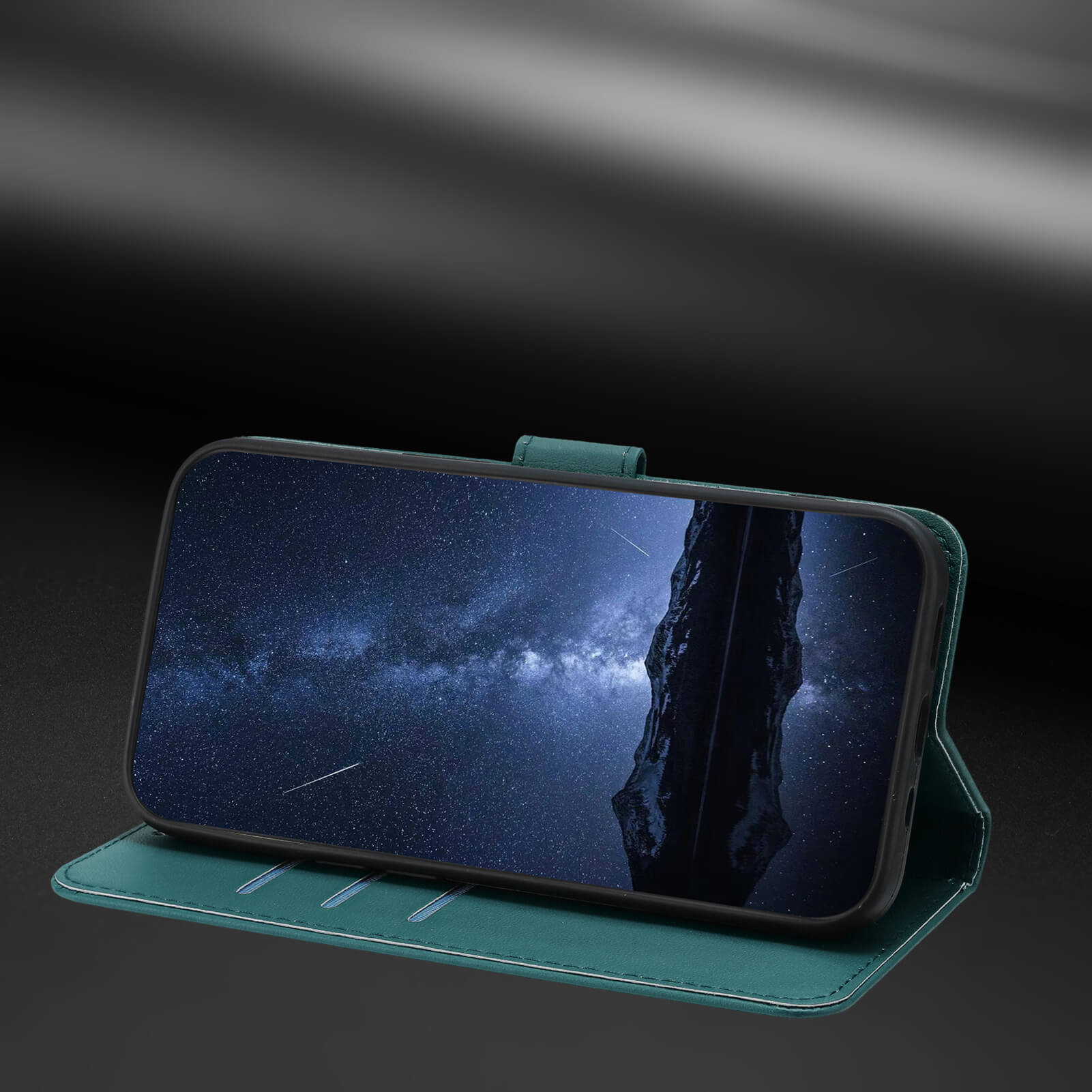 Eine tealfarbene Cover-Discount iPhone 17 Air - Elegante Ledertasche mit Ständer stützt ein Smartphone, das einen nächtlichen Sternenhimmel auf einer dunklen Oberfläche zeigt.