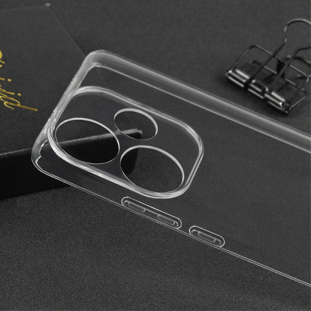 Die transparente Xiaomi Poco F6 Hülle von Cover-Discount aus Silikon mit großen Kameraausschnitten liegt auf dunklem Untergrund neben einer Büroklammer und schwarzer Box.