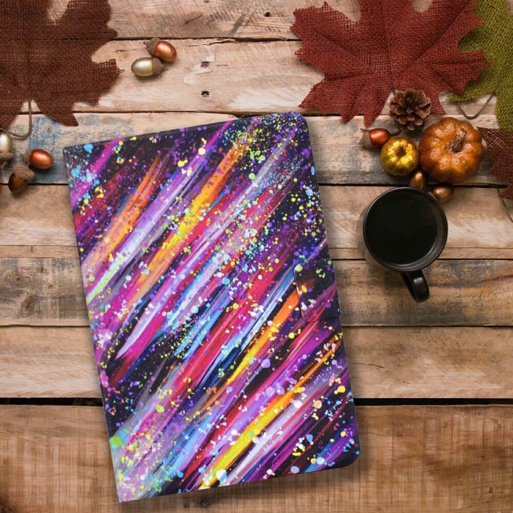 Ein buntes Notizbuch, schwarzer Kaffee, ein Cover-Discount Kindle Paperwhite 2024 Etui mit stilvollem Motiv und herbstliche Dekoration auf einem Holztisch schaffen einen gemütlichen Arbeitsbereich.