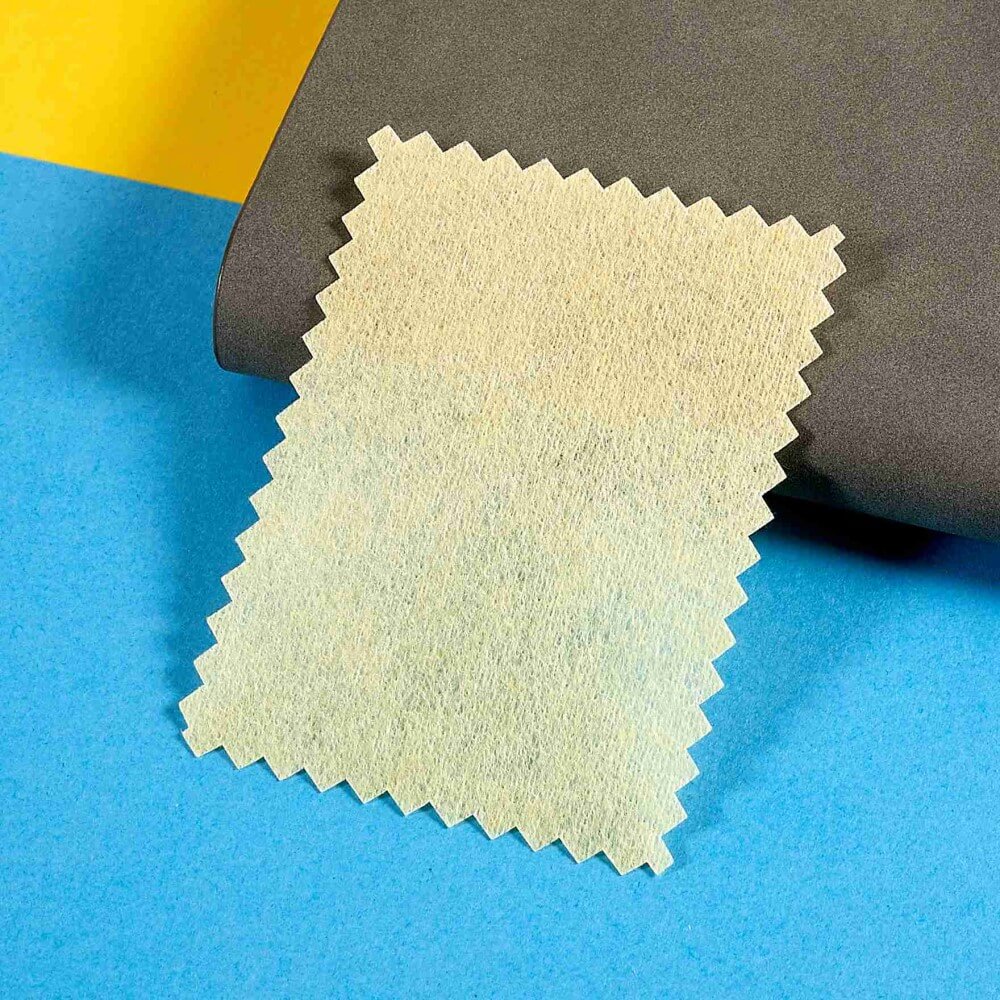 Auf blauem und gelbem Hintergrund erscheint ein beiges strukturiertes Stoffmuster mit Zickzack-Kanten und zeigt kratzfeste Haltbarkeit – wie die Cover-Discount iPhone 16 Display-Schutzfolie aus PET-Material.