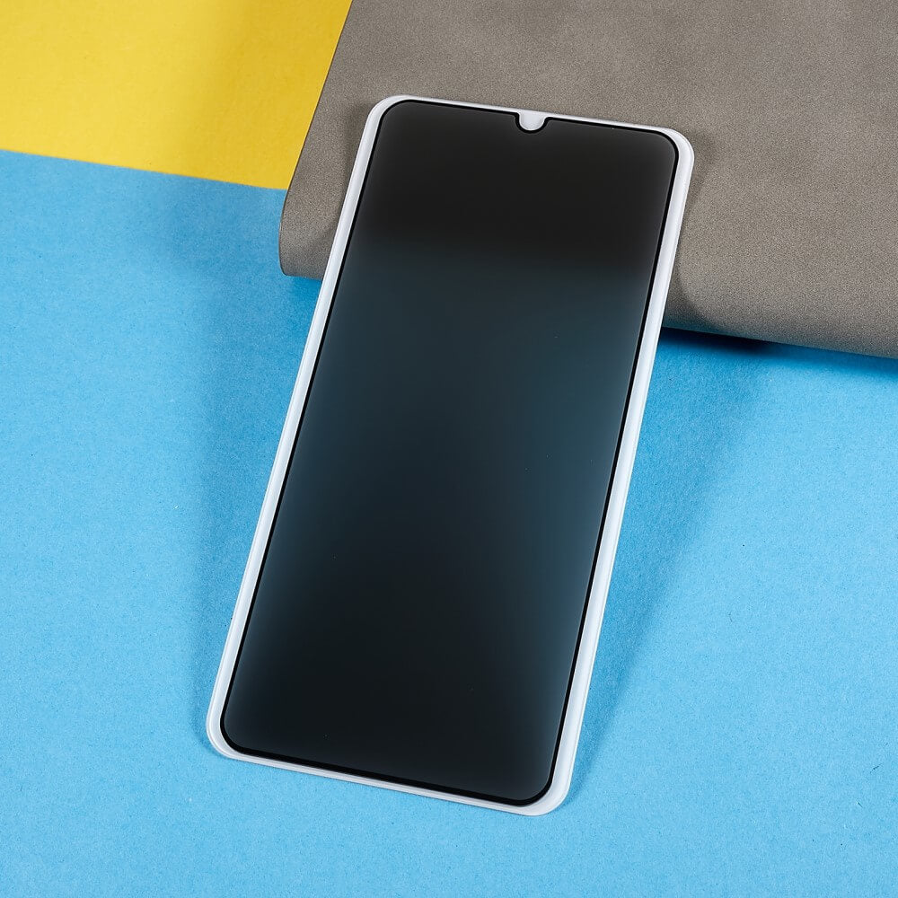 Das Cover-Discount Galaxy A16 – Panzerglas Display Privacy Anti-Spy Smartphone mit schwarzem Bildschirm liegt auf einer blauen Oberfläche neben einem grau-gelben Hintergrund.