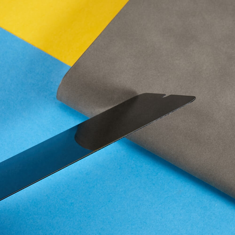 Ein Galaxy A16 Panzerglas Display Privacy Anti-Spy von Cover-Discount liegt auf blauem Papier neben einem grauen Blatt auf gelbem Hintergrund.