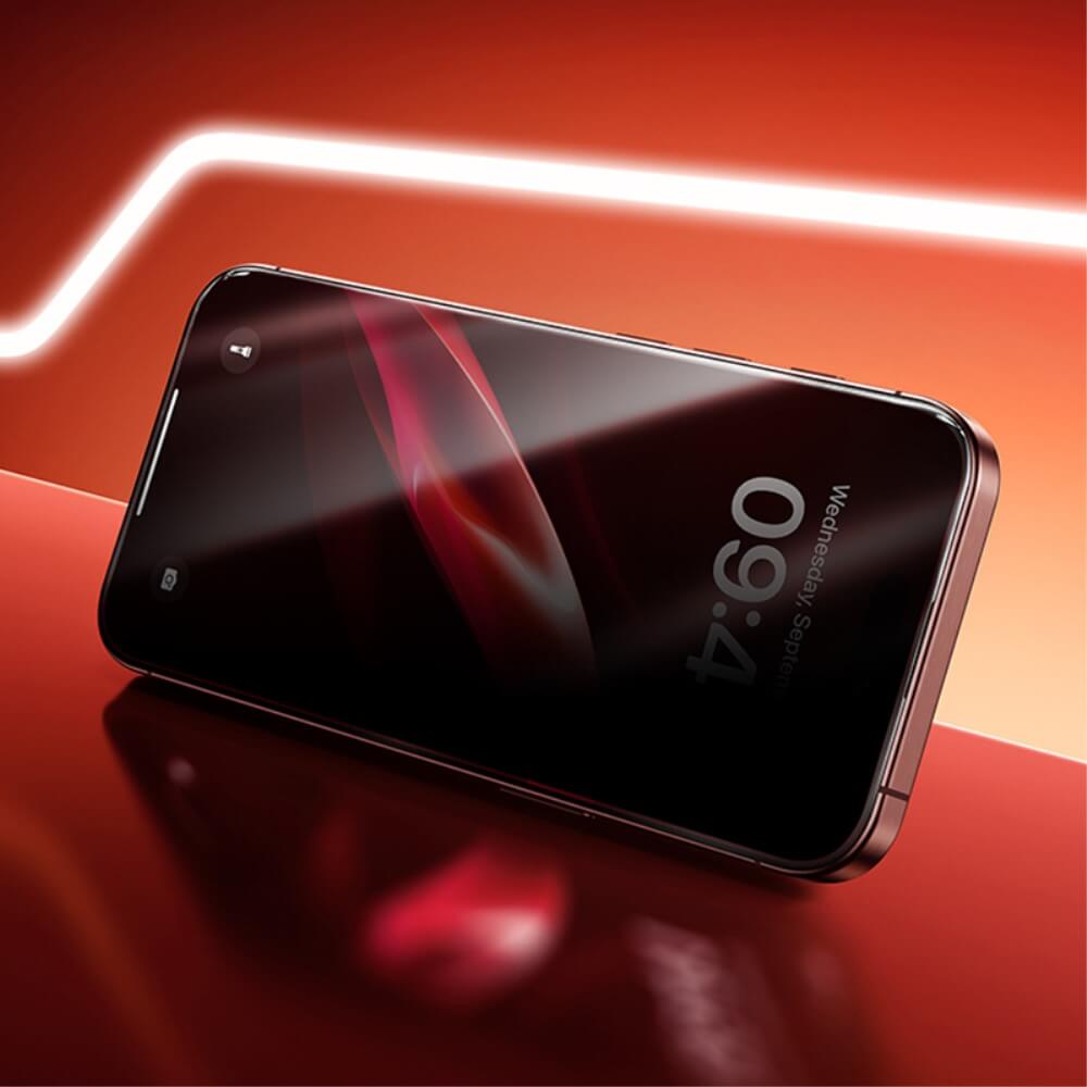 Das Panzerglas Display Privacy Anti-Spy von Cover-Discount für das iPhone 16/15/14 Pro verfügt über einen eleganten, dunklen Bildschirm auf einer glänzend roten Oberfläche mit hellem diagonalem Licht – ideal für datenschutzbewusste Benutzer.