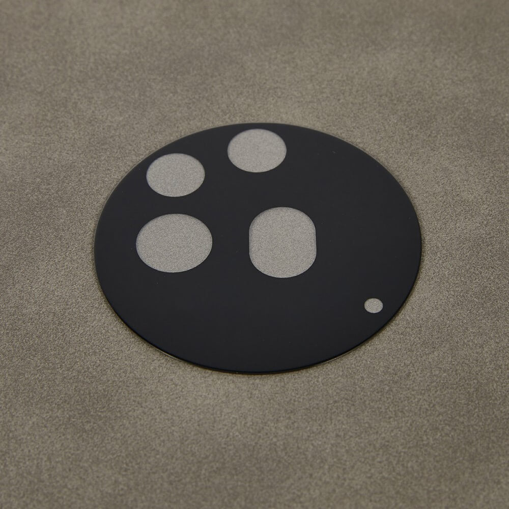 Die mit vier Aussparungen ausgestatteten Panzerglas-Kameraobjektivabdeckungen von Cover-Discount Nothing Phone (3a) Pro – 2 Stk. liegen auf einer strukturierten grauen Oberfläche und bieten zuverlässigen Kameraschutz.