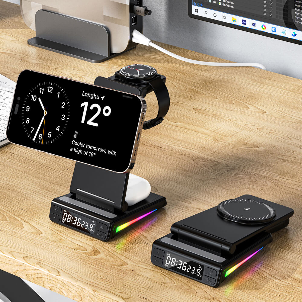 Zwei Cover-Discount.ch Multifunktionale magnetische kabellose Ladestationen mit LED-Uhranzeige laden Smartphone, Earbuds und Smartwatch nebeneinander auf einen Schreibtisch neben einem Computerbildschirm.