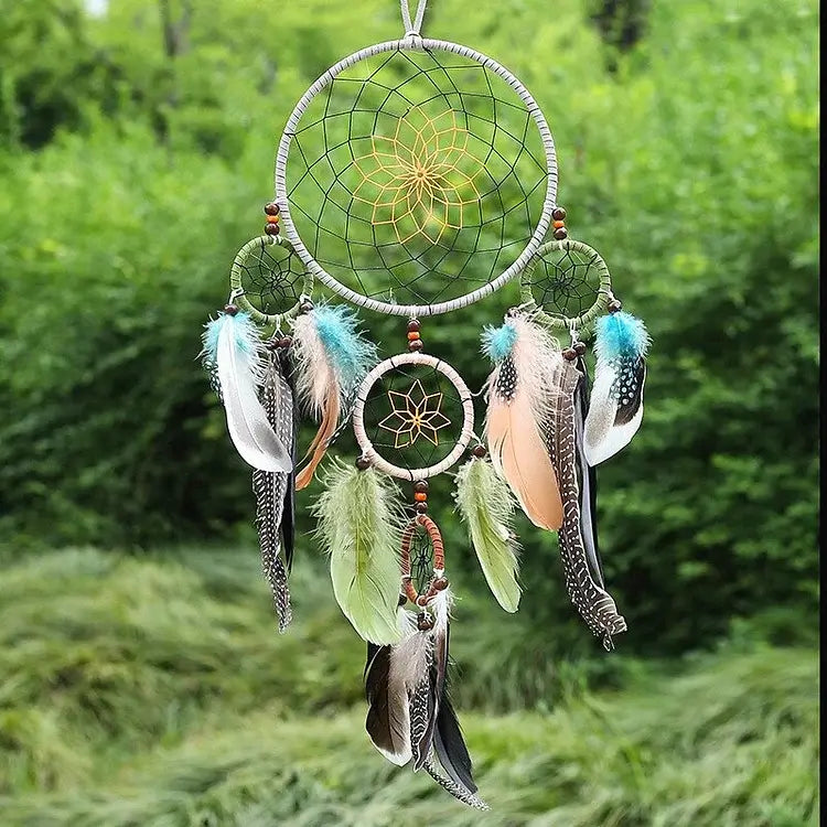 Der „Stilvoller Traumfänger mit 5 Ringen in Naturtönen“ von Cover-Discount hängt als dekoratives Highlight im Freien vor grünem Laub und Gras.