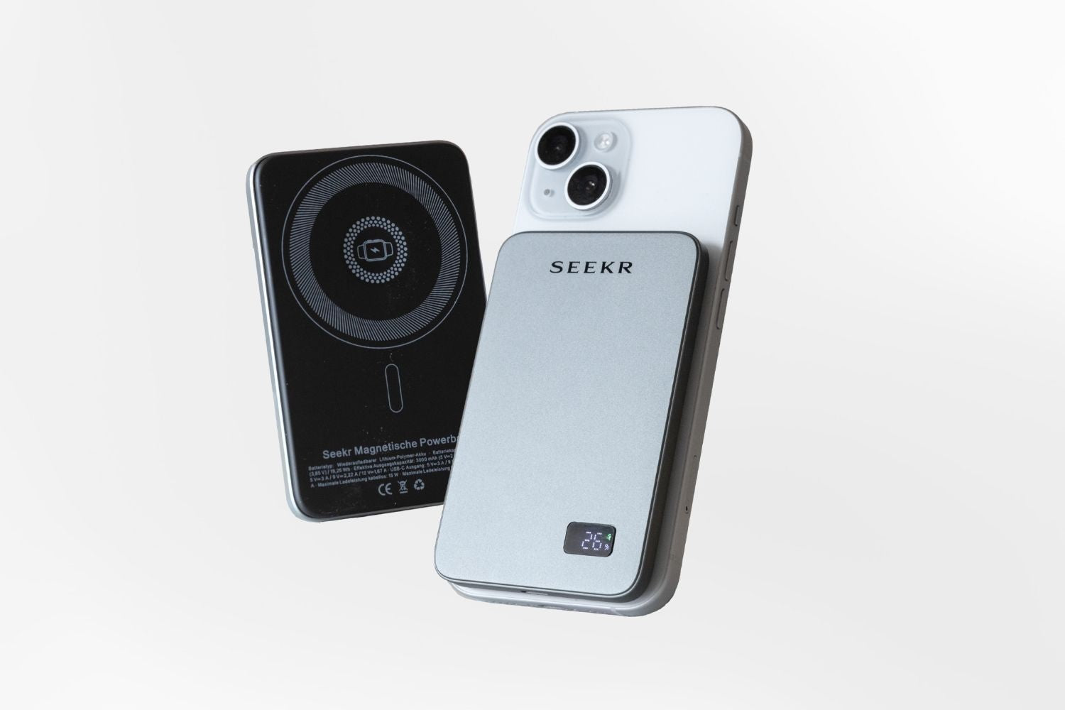 Ein SEEKR SWISS Power Mag - Schwarz 5000 mAh ist auf der Rückseite eines weissen Smartphones für kabelloses Schnellladen befestigt, mit einer weiteren Powerbank in der Nähe.