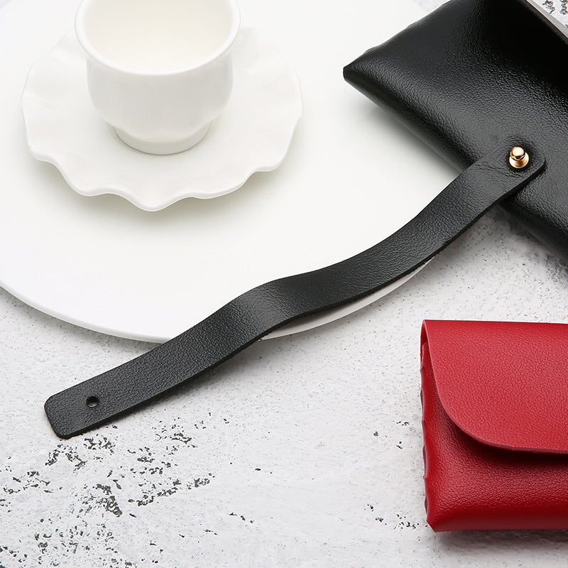 Ein Cover-Discount Premium Brillenetui aus Kunstleder Business, ein schwarzes Band in Form einer Teetasse und eine rote Brieftasche auf einer weißen strukturierten Oberfläche.