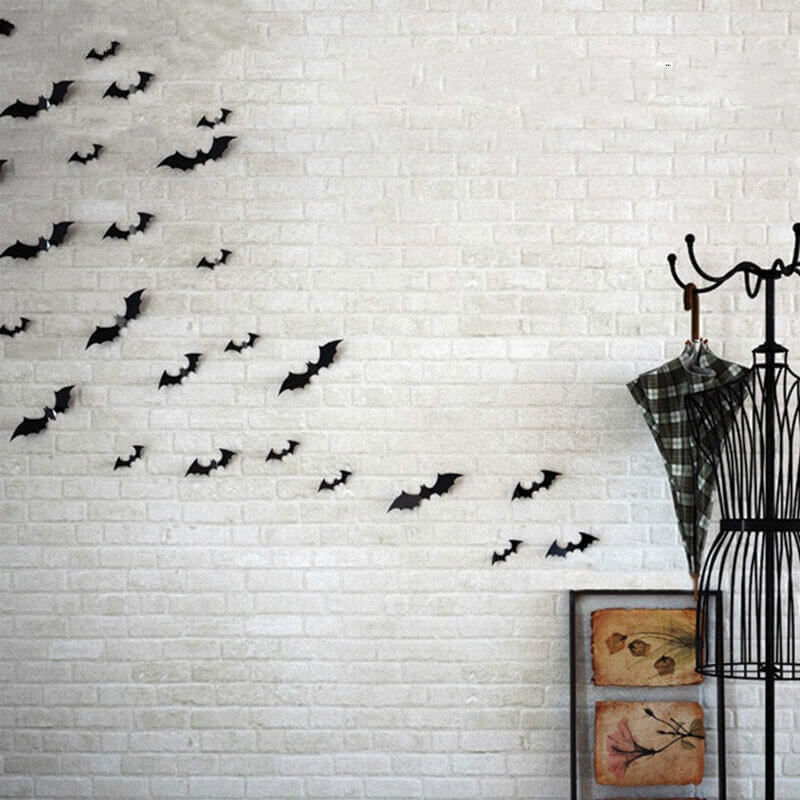 Die 12 Stk. 3D Fledermäuse Wand Sticker Deko von Cover-Discount setzen auf einer weißen Backsteinwand mit Garderobe, Schirm und gerahmtem Bild stilvolle Akzente für eine einzigartige Halloween-Deko.