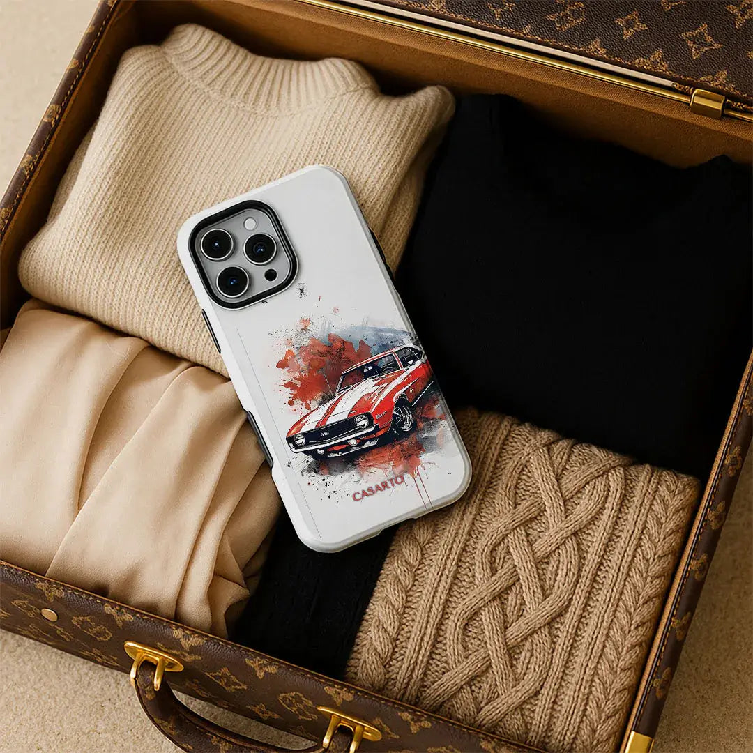 Ein Koffer mit gefalteten Pullovern und ein iPhone 17 Pro Max in einer Casarto Handyhülle Camaro, MagSafe kompatibel, darauf ruhend.