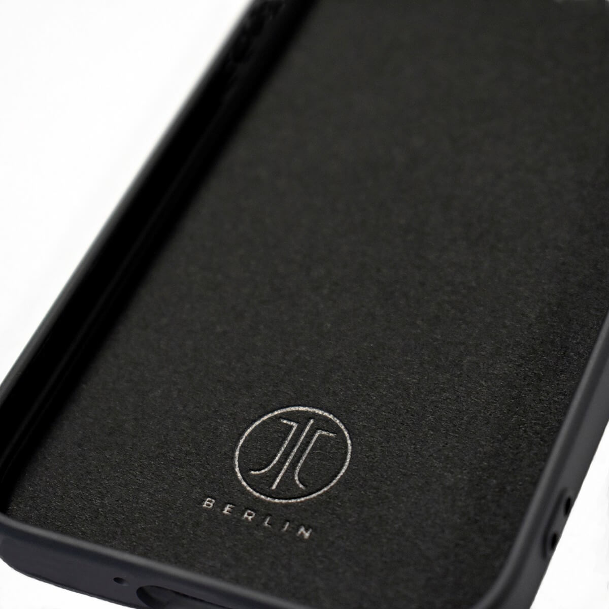Nahaufnahme einer schwarzen JT Berlin Pankow Soft-Hülle mit einem kreisförmigen, auf das Innenfutter geprägten JT Berlin-Logo, die als elegante Hülle für das Galaxy A37 konzipiert ist.