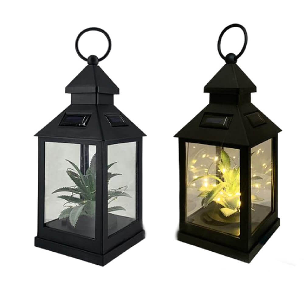 Zwei schwarze Laternen mit Glasplatten, in denen jeweils eine kleine Pflanze sitzt; eine davon ist die Cover-Discount Solar Tischlampe LED Laterne, die sanft warmweißes Licht ausstrahlt.
