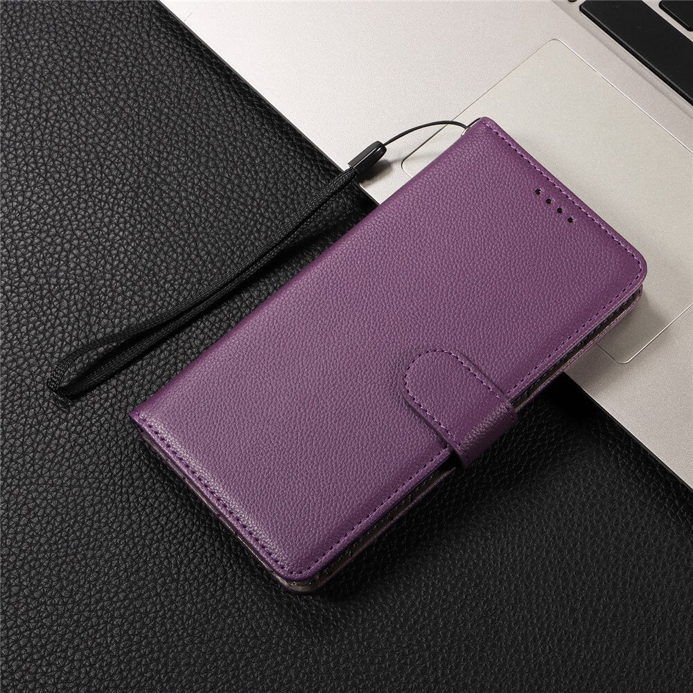 Eine iPhone 17 Pro Lederoptik-Hülle von Cover-Discount mit strukturierter Oberfläche, Brieftaschenfunktion und Schlaufe liegt auf schwarzem Untergrund neben einem Laptop.