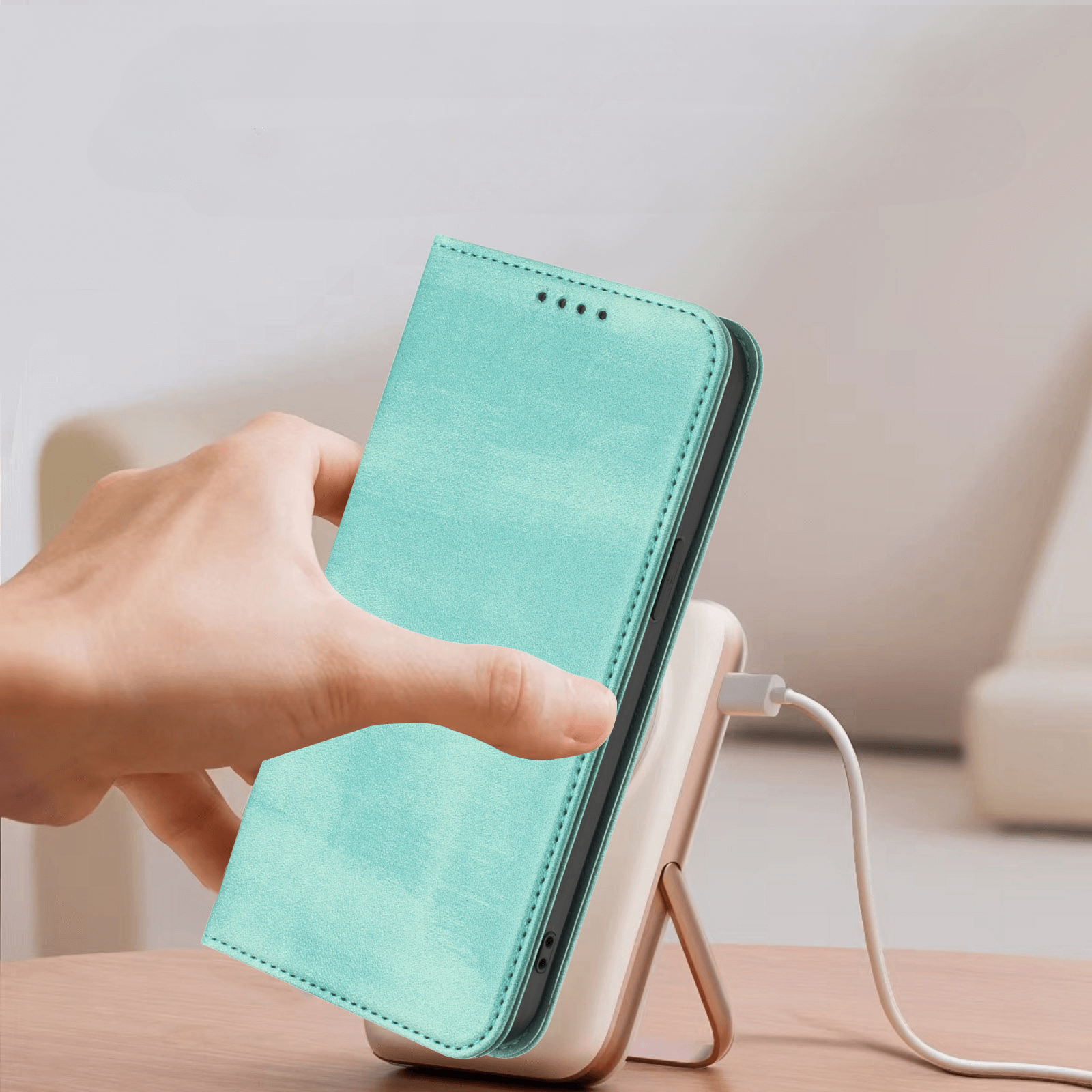 Eine Hand legt ein türkisfarbenes Cover-Discount iPhone 17 Air - Vintage Flip Case mit RFID-Schutz auf eine weiße kabellose Ladestation.