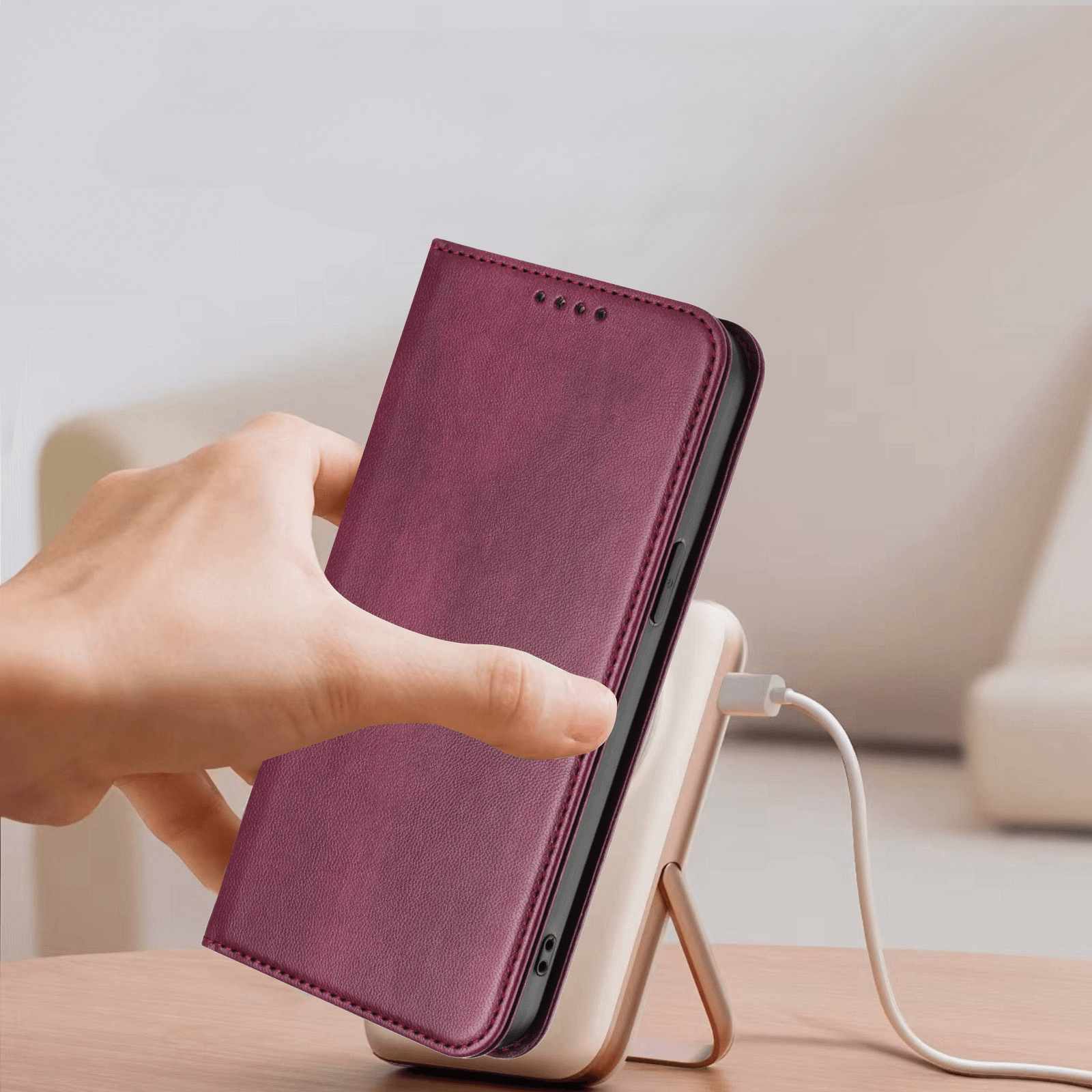 Eine Hand legt ein Cover-Discount iPhone 17 Air - Vintage Flip Case mit RFID-Schutz und einer lila Hülle auf eine kabellose Ladestation auf einem Tisch.