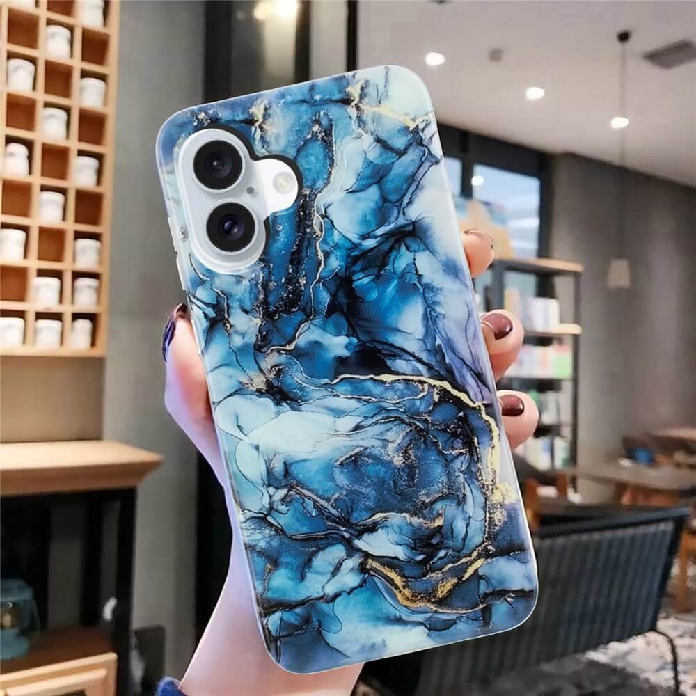 In einem modernen Café hält eine Hand die Cover-Discount iPhone 17 - Silikon Hülle mit Marmor Motiv in Blau-Gold - stilvolles Design und optimalen Schutz vereint.