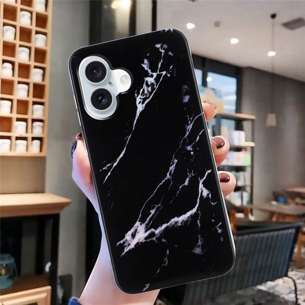 Eine Hand hält die Cover-Discount iPhone 17 - Silikon Hülle mit Marble Motiv in schlichtem Schwarz und präsentiert Stil und Schutz in einem modernen, gut beleuchteten Café.