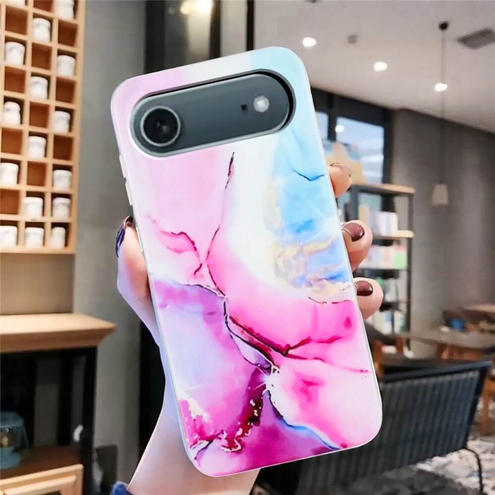 Eine Hand hält die Cover-Discount iPhone 17 Air Silikon Hülle mit Marble Motiv in Pink und Blau in einem modernen Café.