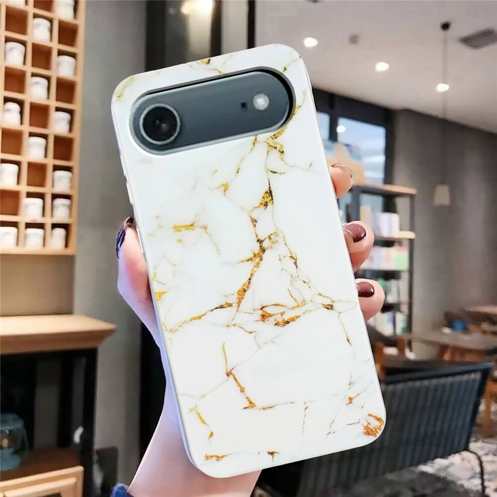 Eine Hand hält die Cover-Discount iPhone 17 Air Silikon Hülle mit Marble Motiv in Weiß und Gold in einem modernen, gemütlichen Raum.