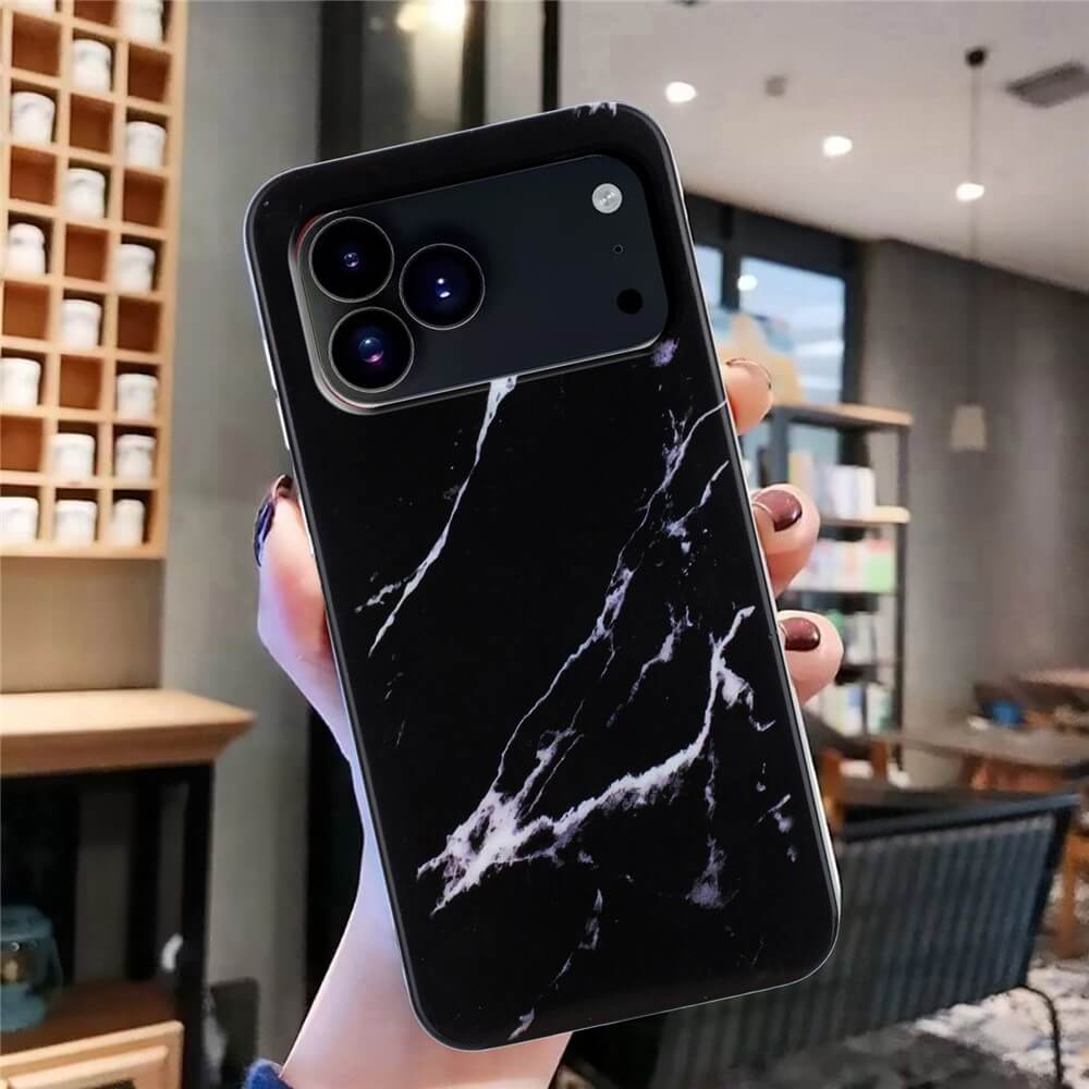 Eine Hand hält die Cover-Discount iPhone 17 Pro Max - Silikon Hülle mit Marble Motiv in einem modernen, gut beleuchteten Café.