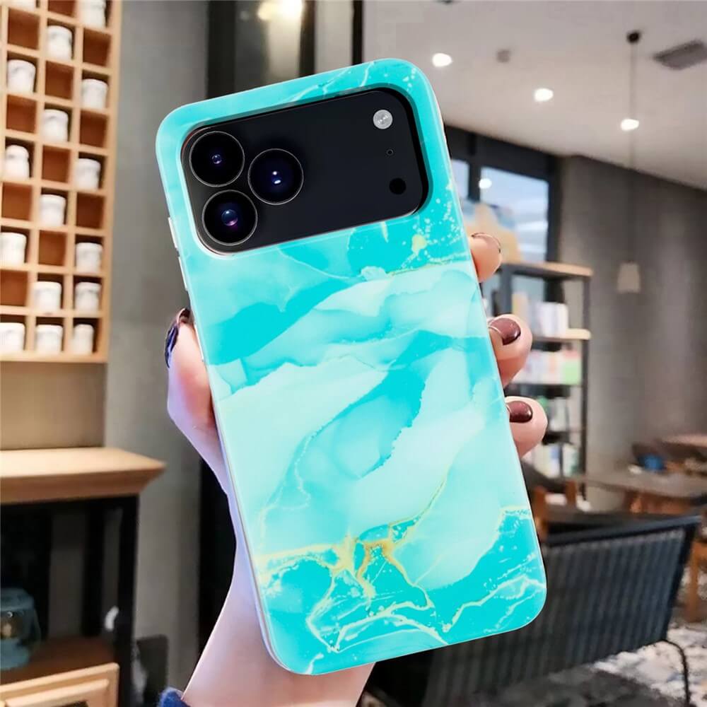 Eine Hand hält ein iPhone 17 Pro Max in einer blauen Marmor Silikon Hülle von Cover-Discount, in einem modernen, gut beleuchteten Café.