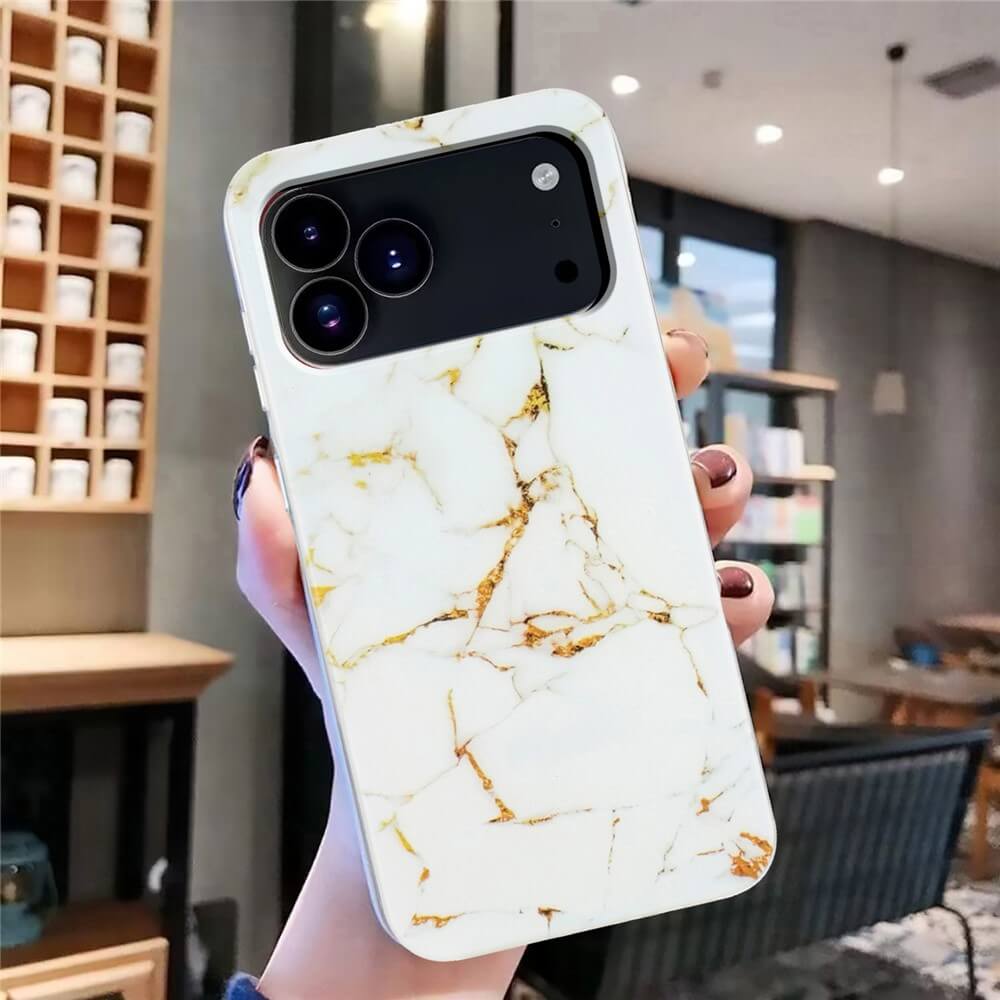 Eine Hand hält ein iPhone 17 Pro Max in einer weiß-goldenen, marmorierten Silikonhülle von Cover-Discount in einer modernen Innenraumumgebung.