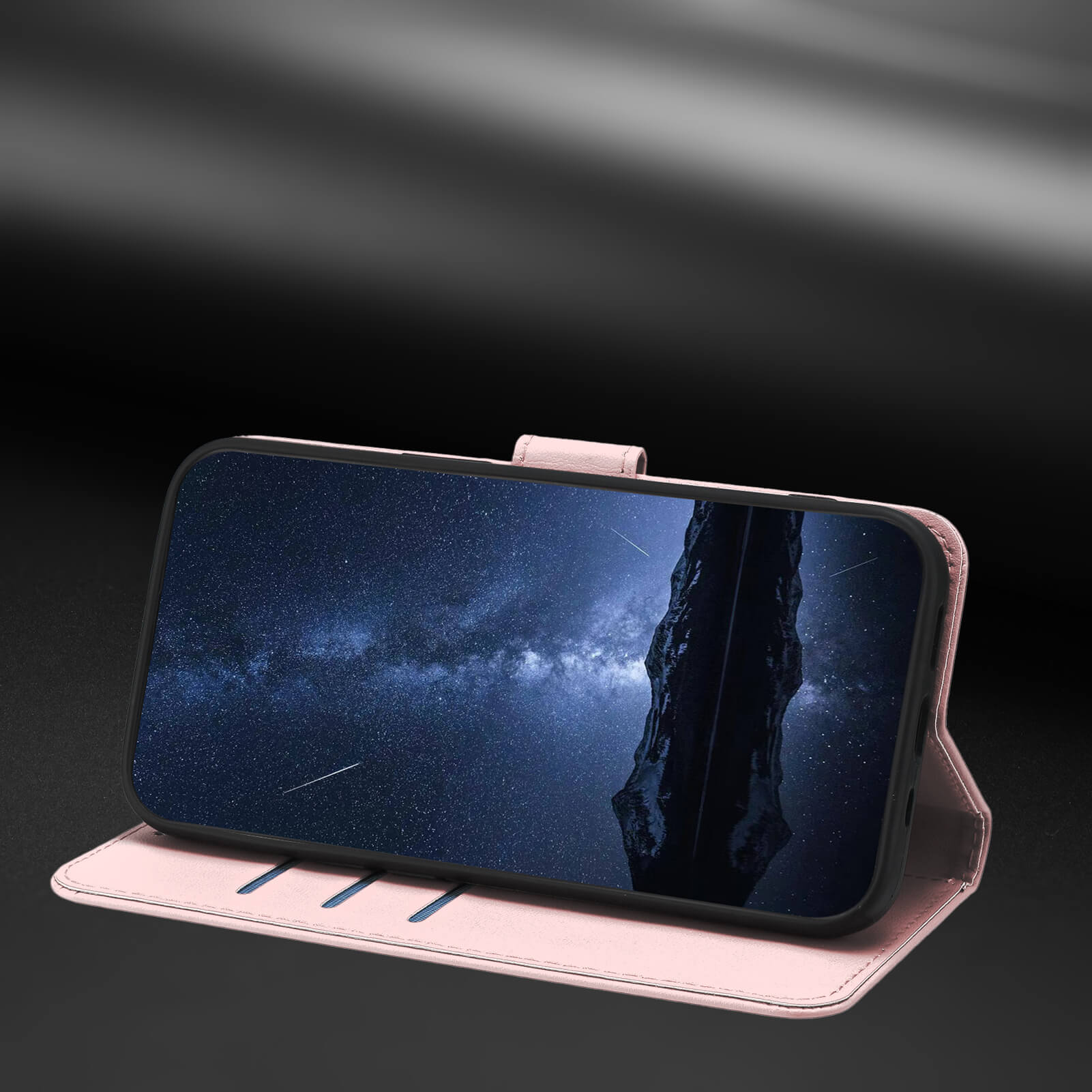 Ein iPhone 17 Pro Max in einer rosafarbenen "Eleganten Ledertasche" von Cover-Discount mit Standfunktion zeigt einen nächtlichen Sternenhimmel, aufgestützt auf einer dunklen Fläche.
