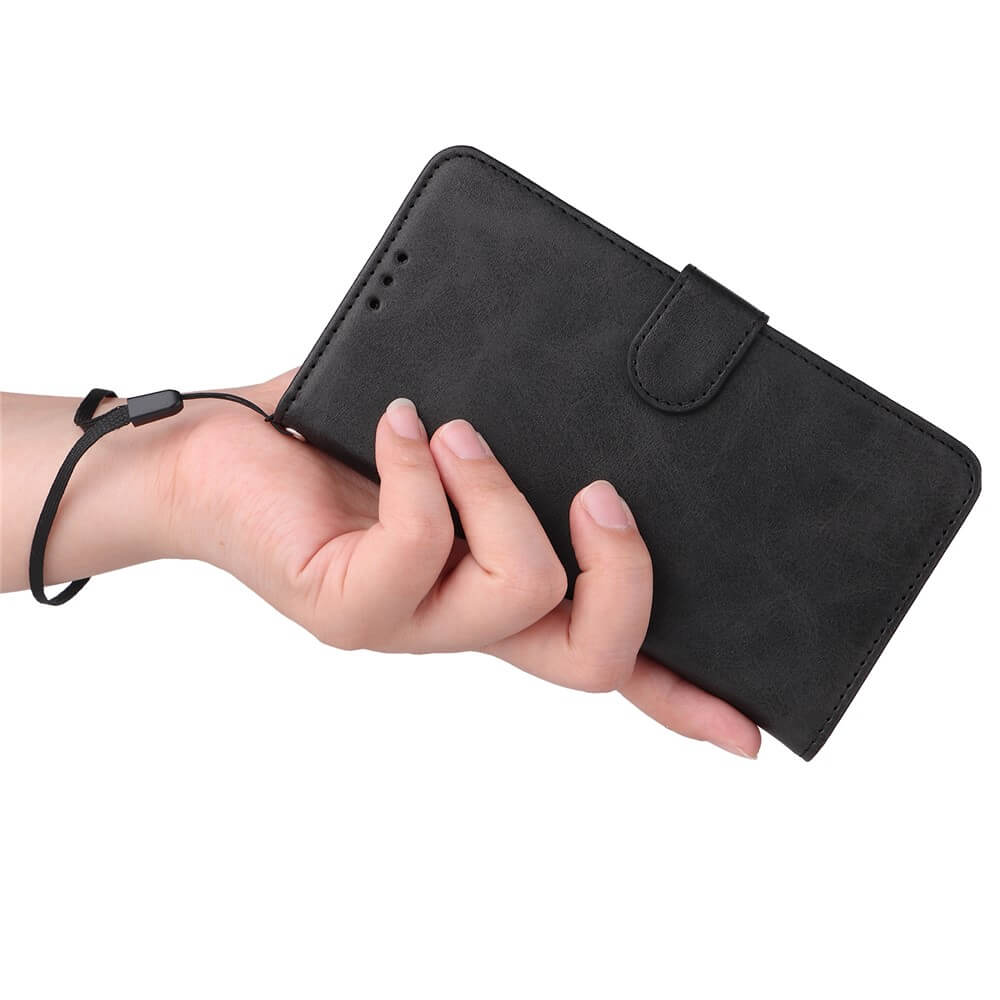 Hand hält schwarze Lederhülle mit verstellbarem Handgelenkriemen für Smartphones.
