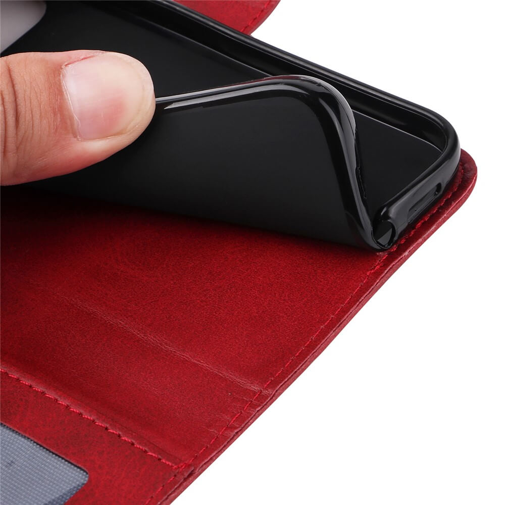Daumen und Zeigefinger entfernen eine schwarze flexible Handyhülle von einer roten Lederhülle mit Naht und Ausweisfach.