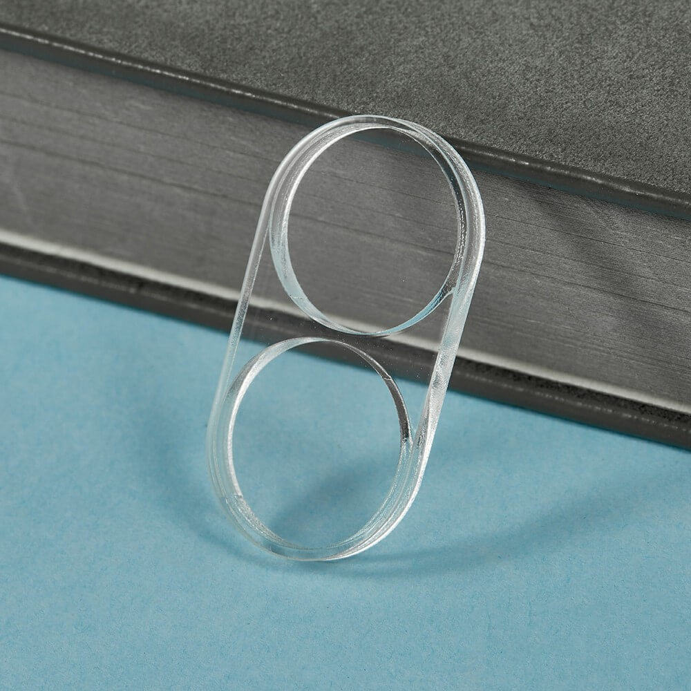 Die Cover-Discount Galaxy Z Flip7 - 2 Stk. Schutzglas Kamera ruht gegen ein geschlossenes, gebundenes Buch auf einer blauen Oberfläche.