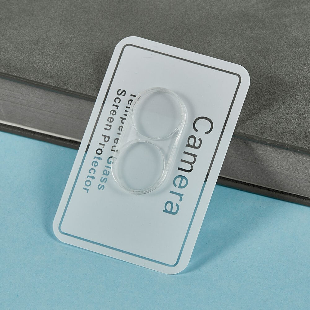 Ein Cover-Discount Galaxy Z Flip7 - 2 Stk. Schutzglas Kamera Objektivschutz in seiner Verpackung, auf einer grauen Oberfläche mit einem blauen Hintergrund platziert.