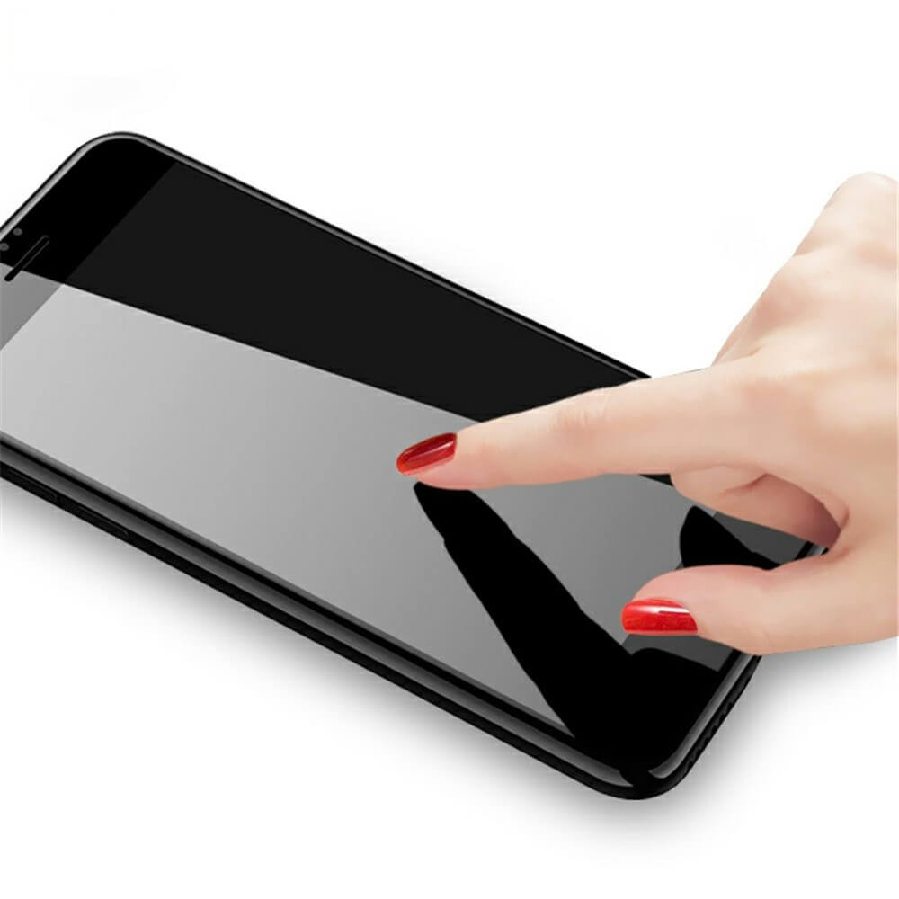 Schwarzes Smartphone mit glänzendem Bildschirm auf weißer Fläche, berührt von einer Hand mit roten Nägeln.