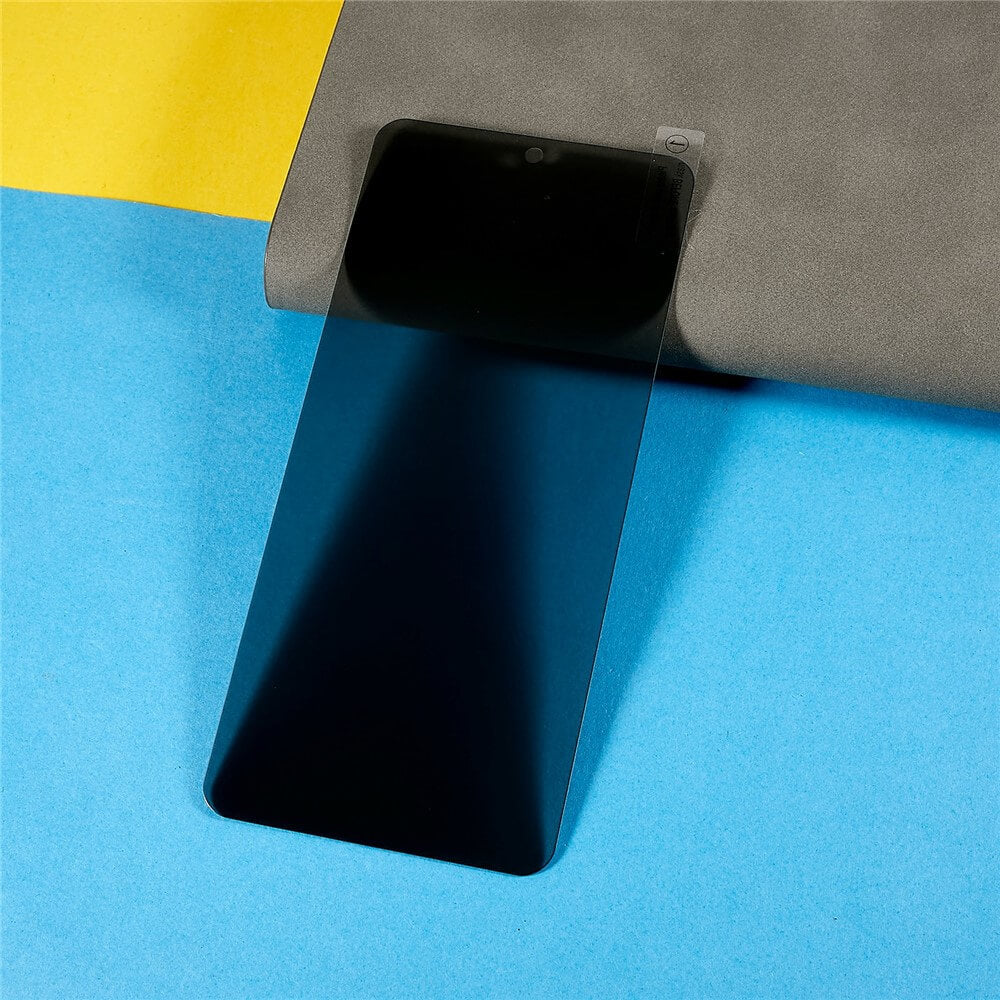 Smartphone mit transparentem, blauem Displayschutz und grauem Stoff auf gelb-blauem Hintergrund.
