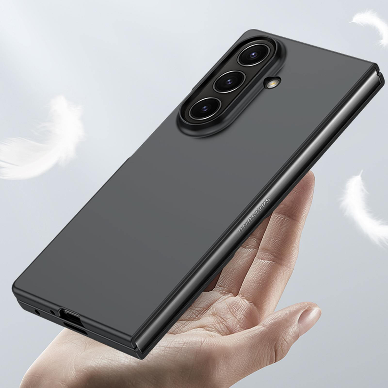 Eine Hand hält ein elegantes schwarzes Smartphone mit drei Kameras in einer Cover-Discount Galaxy Z Fold7 Schützende Hartplastik Handyhülle, während weiche weiße Federn in der Nähe schweben, um das leichte und dennoch schützende Design der Hülle zu unterstreichen.